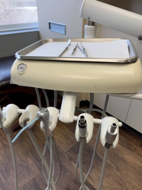 Denver, Colorado, ABD-17 Şubat 2024. Geleneksel tükürük lavabosu ve bir dizi el işi aletleri içeren dişçi çalışma istasyonunun temel araçları. Kurulum, profesyonel bir dişçiye işaret ediyor.