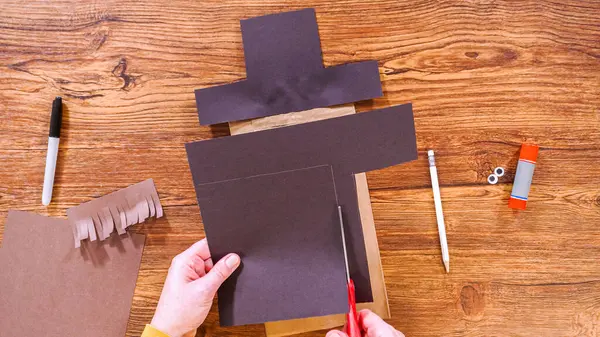 Adım adım. Düz yatıyordu. Öğretmen, kahverengi bir çantadan kağıt bir kukla yaparak, çalışma alanı olarak ahşap bir yüzey kullanarak çevrimiçi sınıfa rehberlik ediyor..