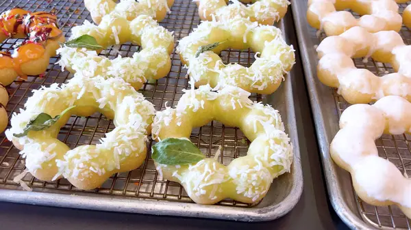 Metal tepsilerde çeşitli malzemelerle taze pişmiş mochi çörekleri eşsiz şekillerini ve şekerli kaplamalarını vurguluyor..