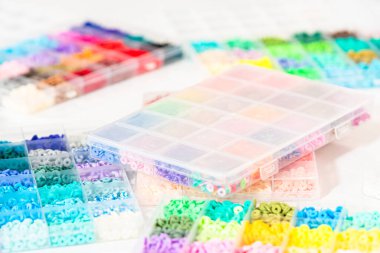 Beyaz bir masaya yerleştirilmiş çeşitli kil boncuk kutuları yaratıcı çocukların el sanatları projesini bekliyor..