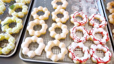 Metal tepsilerde çeşitli malzemelerle taze pişmiş mochi çörekleri eşsiz şekillerini ve şekerli kaplamalarını vurguluyor..