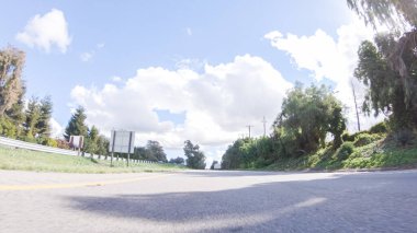 Açık bir kış gününde, bir araba, Santa Maria, California yakınlarındaki 101. Otoyol boyunca yeşil ve altın renkli bir karışımla çevrili, parlak mavi bir gökyüzünün altında sorunsuzca seyahat eder..