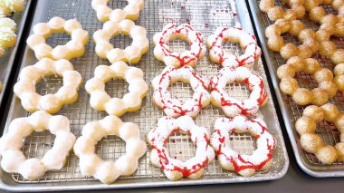 Metal tepsilerde çeşitli malzemelerle taze pişmiş mochi çörekleri eşsiz şekillerini ve şekerli kaplamalarını vurguluyor..