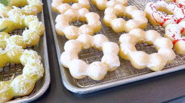 Metal tepsilerde çeşitli malzemelerle taze pişmiş mochi çörekleri eşsiz şekillerini ve şekerli kaplamalarını vurguluyor..