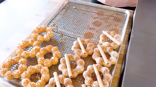Metal tepsilerde çeşitli malzemelerle taze pişmiş mochi çörekleri eşsiz şekillerini ve şekerli kaplamalarını vurguluyor..