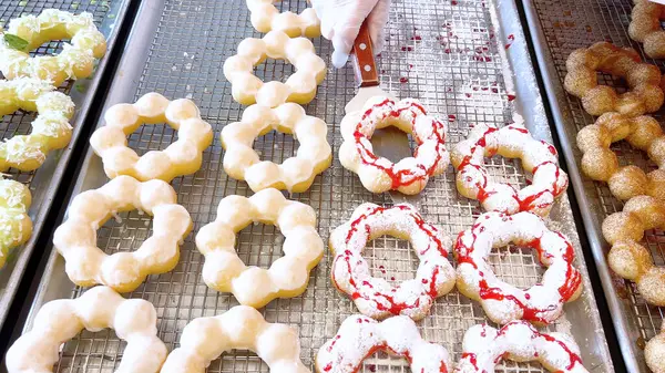 Metal tepsilerde çeşitli malzemelerle taze pişmiş mochi çörekleri eşsiz şekillerini ve şekerli kaplamalarını vurguluyor..