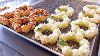 Metal tepsilerde çeşitli malzemelerle taze pişmiş mochi çörekleri eşsiz şekillerini ve şekerli kaplamalarını vurguluyor..