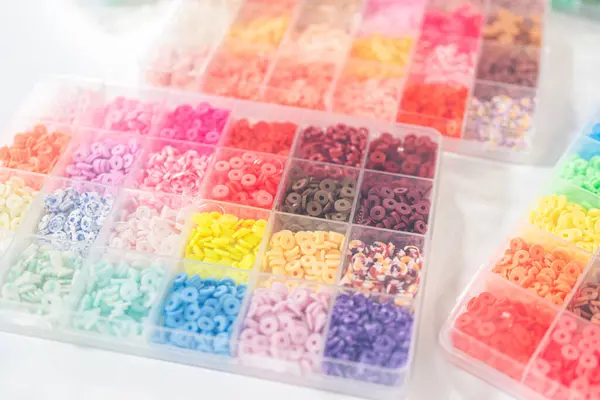 Beyaz bir masaya yerleştirilmiş çeşitli kil boncuk kutuları yaratıcı çocukların el sanatları projesini bekliyor..