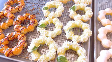 Metal tepsilerde çeşitli malzemelerle taze pişmiş mochi çörekleri eşsiz şekillerini ve şekerli kaplamalarını vurguluyor..