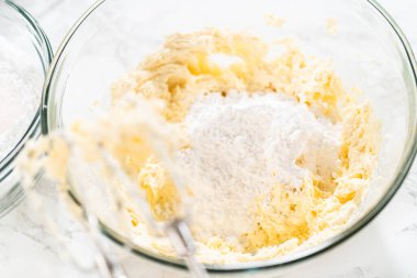 Zengin, pürüzsüz bir krem peynirli krema hazırlamak için el çırpma makinesi kullanarak malzemeleri ustalıkla birleştirirsin ki bu da kekin süslemesi için mükemmeldir..