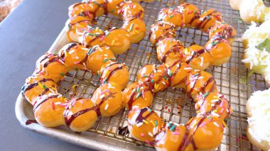 Metal tepsilerde çeşitli malzemelerle taze pişmiş mochi çörekleri eşsiz şekillerini ve şekerli kaplamalarını vurguluyor..