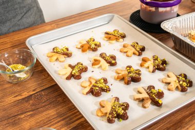 Çikolataya batırılmış yıldız şeklinde tatil kurabiyeleri ve ezilmiş şam fıstığı serpiştirmek. Parşömen kağıdına yerleştirilmiş..