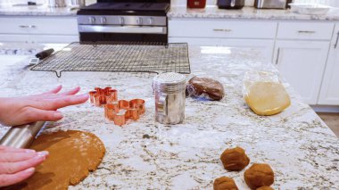 Modern bir mutfaktaki zarif mermer tezgahın üzerine zencefilli kurabiye hamuru sermek için ayarlanabilir bir merdane kullanmak, bayram pişirme şenliğine hazırlanmak....