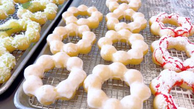 Metal tepsilerde çeşitli malzemelerle taze pişmiş mochi çörekleri eşsiz şekillerini ve şekerli kaplamalarını vurguluyor..