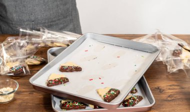 Dikkatlice paketlenmiş Noel kurabiyeleri, çikolataya batırılmış ve şeffaf selofan ambalajla sunulmuş, bayram hediyesi olarak mükemmel..