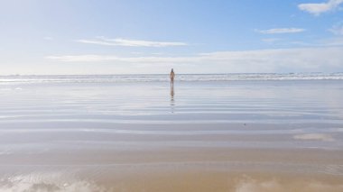Küçük kız, soğuğa göğüs geriyor, kışın sahilde mayosuyla koşuyor..