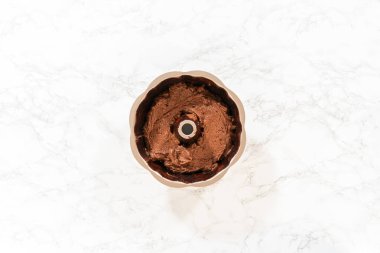 Düz yatıyordu. Hazırlanan hamur, lezzetli bir çikolatalı kek için zemin hazırlayan yağlı tavaya dikkatlice dolduruluyor..