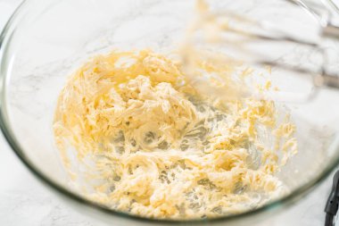 Mayasız tarçınlı çörekler için krem peynirli krema yapmak için karıştırma kabındaki malzemeleri karıştırıyorum..