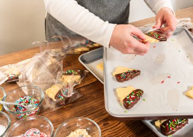 Dikkatlice paketlenmiş Noel kurabiyeleri, çikolataya batırılmış ve şeffaf selofan ambalajla sunulmuş, bayram hediyesi olarak mükemmel..