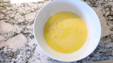 Elinde kırmızı bir spatula, çırpılmamış tavada çırpılmış parlak yumurtalar, alttaki gaz sobasının mavi alevi, sıcak ve doyurucu bir yemeği garantiliyor..