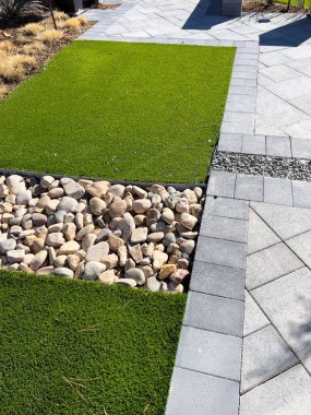 Modern peyzaj tasarımı doğal çakıl taşları ve yapılandırılmış patikalara zıt canlı yapay çim içerir, düşük bakımlı ama estetik olarak tatmin edici bir dış mekan sunar..