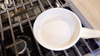 İki mükemmel kızarmış güneşli yumurta çubuksuz bir tavada oturur, kırmızı silikon bir spatula servis etmeye hazırdır, hepsi ocağın tepesinde..