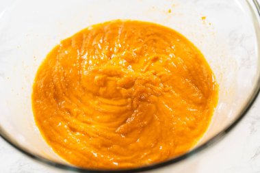 Ağız sulandırıcı ev yapımı balkabağı pastası için büyük bir karıştırma kabında ustalıkla harmanlanmış malzemelerin yakın çekimi..