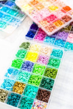 Beyaz bir masaya yerleştirilmiş çeşitli kil boncuk kutuları yaratıcı çocukların el sanatları projesini bekliyor..