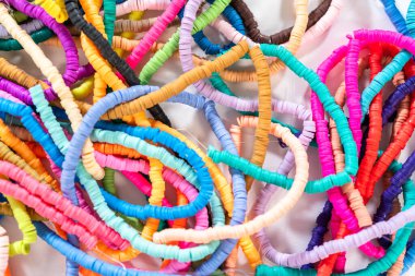 Beyaz bir masadaki renklere göre düzenlenmiş canlı bir kil boncuk koleksiyonu genç zanaatkarlara kendi eşsiz bileziklerini yapmaları için ilham vermeye hazır..