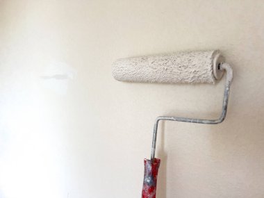 Basit bir ev geliştirme işinin dönüştürücü gücünü sembolize eden, yeni bir beyaz önlük takan bir boya silindirine odaklı bir duvar boyama süreci..