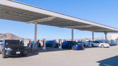 Baker, California, ABD-3 Aralık 2022-Gün boyunca Tesla bir süper şarj istasyonunda yüksek hızlı şarj altyapısını uygun ve verimli bir şekilde kullanan bir Tesla aracı görüldü.
