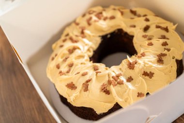 Tuzlu karamel şekerlemeleri ve zencefilli ekmek parçacıklarıyla süslenmiş zencefilli keki dikkatlice hediye etmek için açık pencereli beyaz bir kağıt bohça kek kutusuna yerleştiriyorum..