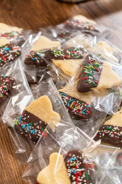 Dikkatlice paketlenmiş Noel kurabiyeleri, çikolataya batırılmış ve şeffaf selofan ambalajla sunulmuş, bayram hediyesi olarak mükemmel..