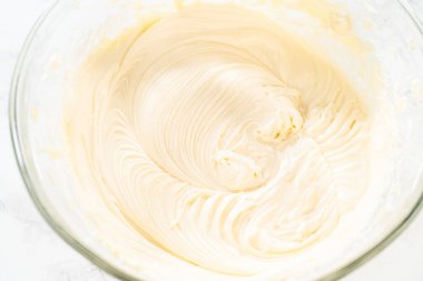 Zengin, pürüzsüz bir krem peynirli krema hazırlamak için el çırpma makinesi kullanarak malzemeleri ustalıkla birleştirirsin ki bu da kekin süslemesi için mükemmeldir..
