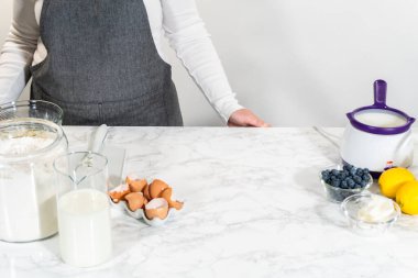 Cam bir kasenin içindeki bileşenleri birleştirmek, bir çırpıcıyla karıştırmak, limonlu-yabanmersinli kek hazırlamak..