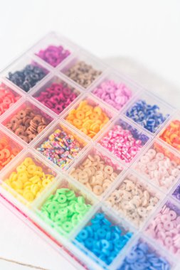 Beyaz bir masaya yerleştirilmiş çeşitli kil boncuk kutuları yaratıcı çocukların el sanatları projesini bekliyor..