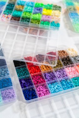 Beyaz bir masaya yerleştirilmiş çeşitli kil boncuk kutuları yaratıcı çocukların el sanatları projesini bekliyor..
