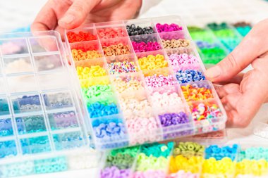 Beyaz bir masaya yerleştirilmiş çeşitli kil boncuk kutuları yaratıcı çocukların el sanatları projesini bekliyor..
