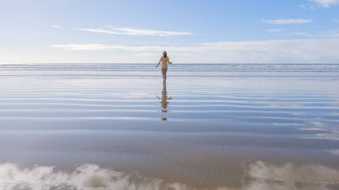 Küçük kız, soğuğa göğüs geriyor, kışın sahilde mayosuyla koşuyor..
