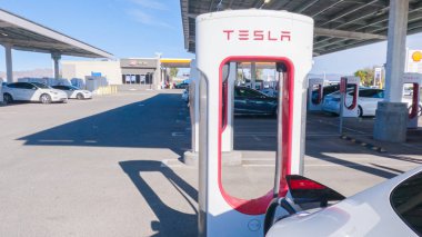 Baker, California, ABD-3 Aralık 2022-Gün boyunca Tesla bir süper şarj istasyonunda yüksek hızlı şarj altyapısını uygun ve verimli bir şekilde kullanan bir Tesla aracı görüldü.