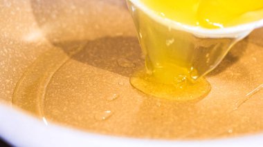 Canlı yumurta sarıları parlıyor, kırmızı spatula benekli tavada yumurta pişiriyor..