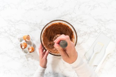 Düz yatıyordu. El çırpma makinesiyle, malzemeler cam karıştırma kabında ustalıkla karıştırılarak nefis bir çikolatalı kek elde ediliyor..
