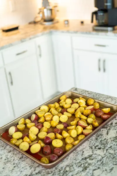 モダンなキッチンでは 半分にされた多色の大理石のジャガイモが シリコーンライナーを並べたベーキングパンに配置されています ローストプロセスは キッチンに口の香りを注入します — ストック写真