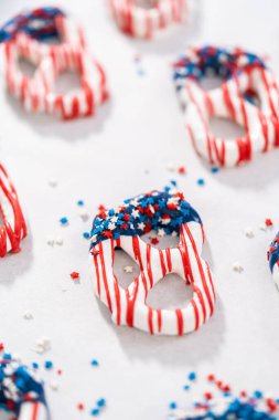 Dipping pretzels twists into melted chocolate to make red, white, and blue chocolate-covered pretzel twists.