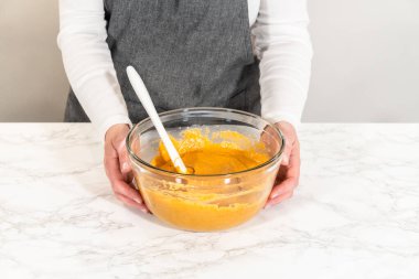 Sıcak bir mutfakta, büyük bir karıştırma kabı malzemelerin ustalıkla harmanlanması için sahne olur, kek karışımından nefis bir ev yapımı balkabağı pastası hazırlamak için sahne hazırlar.