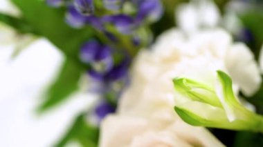 Taze beyaz güllerin ve çeşitli çiçeklerin bulunduğu büyüleyici bir buket, zarif bir vazoda düzenlenmiş, zamansız bir güzellik yayıyor..