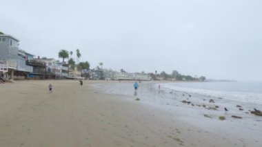 Los Angeles, California, ABD-4 Aralık 2022-POV-Yürürken Miramar Sahili, California kıyılarında bulutlu kış gökyüzü sakin ve yansıtıcı bir atmosfer yaratır..