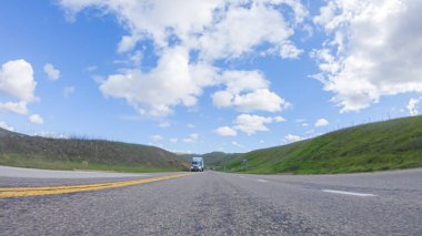 Açık bir kış gününde, bir araba, Santa Maria, California yakınlarındaki 101. Otoyol boyunca yeşil ve altın renkli bir karışımla çevrili, parlak mavi bir gökyüzünün altında sorunsuzca seyahat eder..