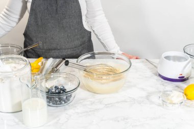 Cam bir kasenin içindeki bileşenleri birleştirmek, bir çırpıcıyla karıştırmak, limonlu-yabanmersinli kek hazırlamak..