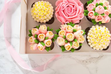 El değmemiş beyaz bir kek kutusunun içinde, her gurme kek bir sanat eseridir, tereyağı kremalı çiçeklerle süslenmiştir, canlı güllere ve lalelere benzemesi için güzelce tasarlanmıştır..